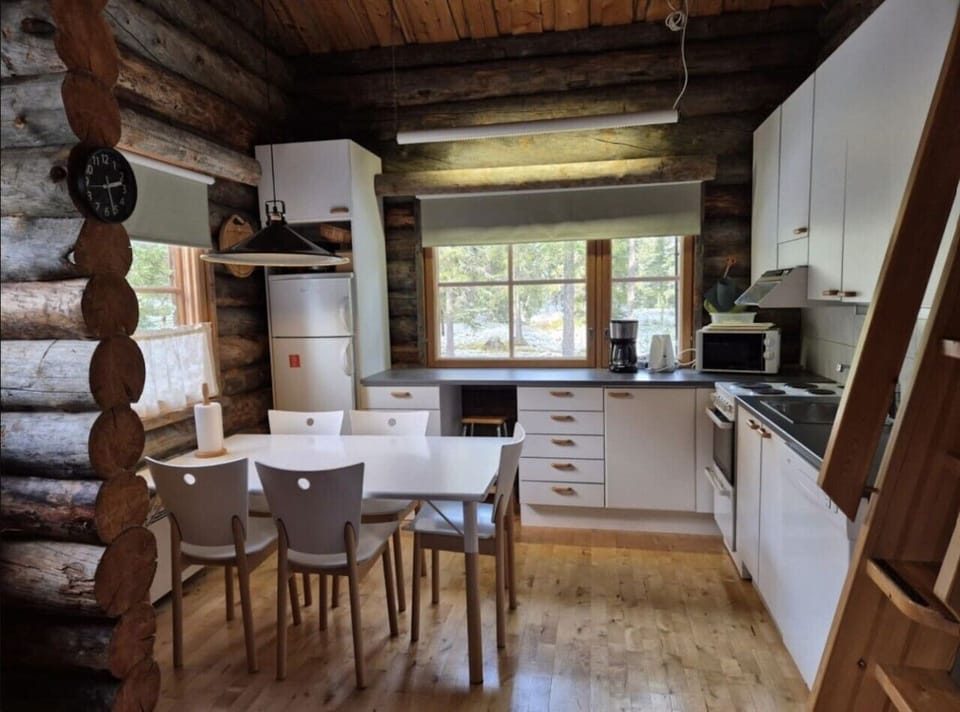 Dining table with chairs in the open-plan kitchen, with a refrigerator, coffee maker and microwave.
