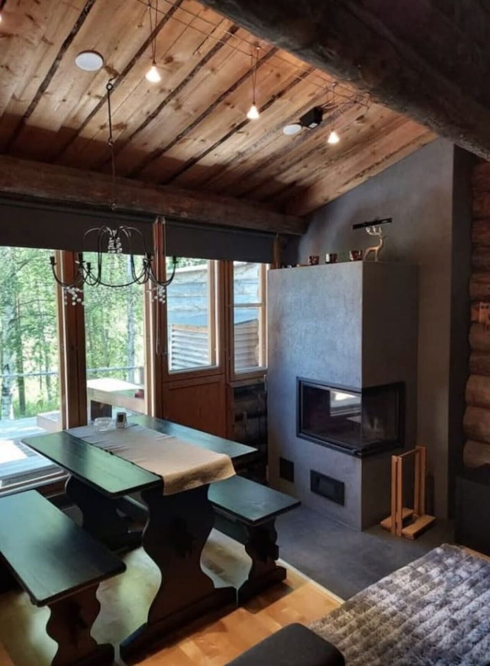 Dining area next to the fireplace with large windows and forest views.