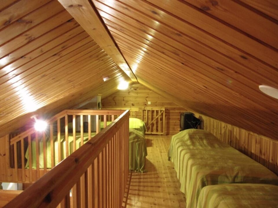 Open loft space with a wooden railing and beds set along the eaves.