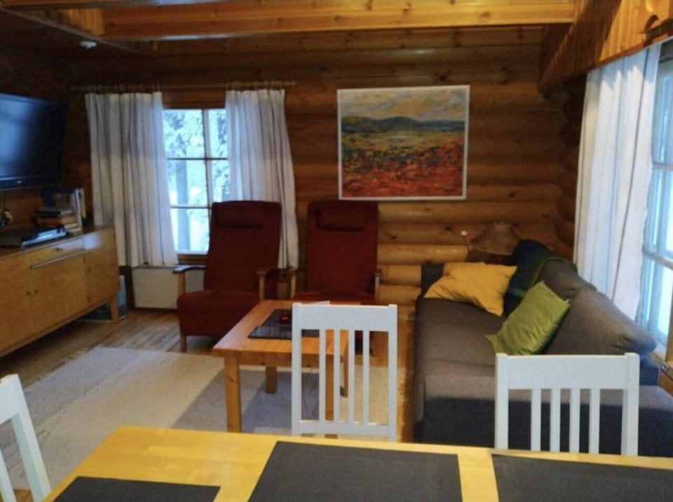 Living room seating area with a television, two armchairs and a sofa.