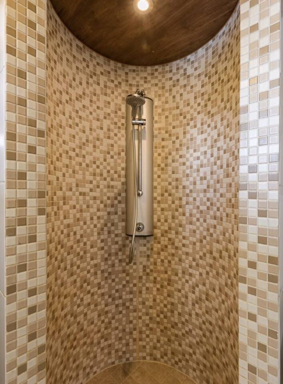 Shower area with mosaic-tiled walls.