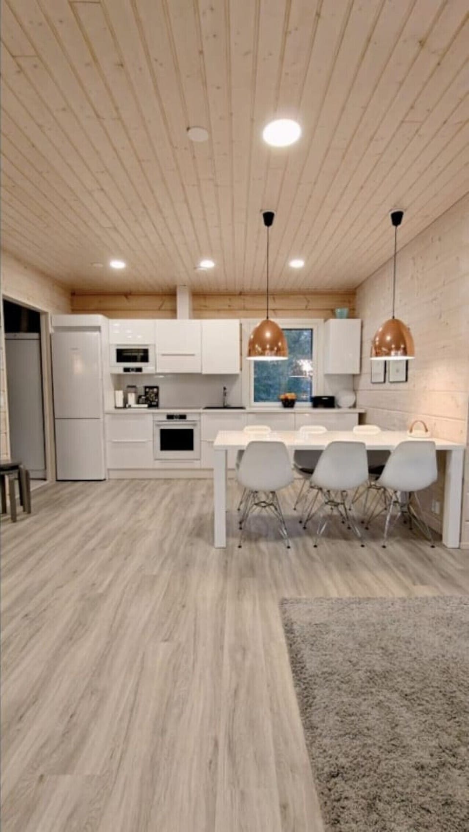 Modern white kitchen with an oven, microwave, coffee maker and a large dining table.