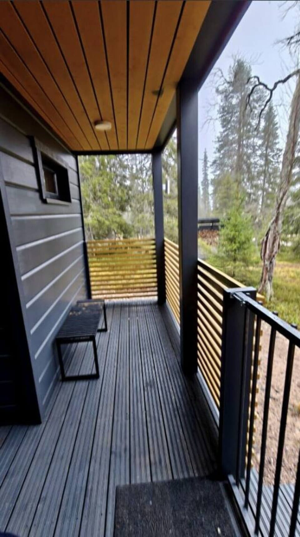 Covered terrace with a bench and views over the surrounding forest.