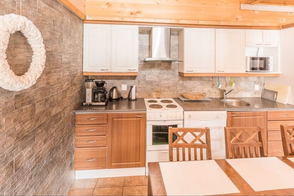 Fully equipped kitchen with an electric stove, coffee maker, and dining table.