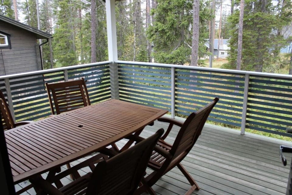 Covered terrace with an outdoor dining table and forest views.