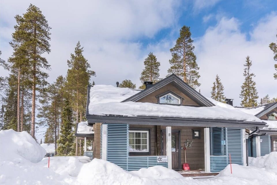 Exterior view of the property surrounded by snow and pine forest in winter.