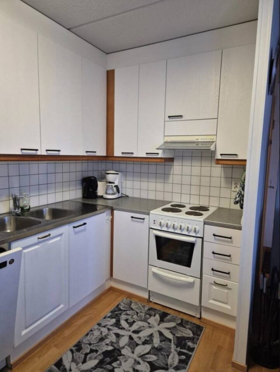 Kitchen with a coffee maker, electric stove with oven, sink and dishwasher.