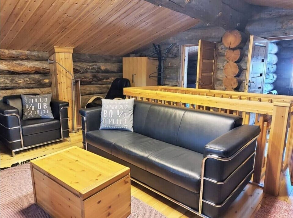 Upstairs lounge area with a leather sofa, an armchair and a wooden coffee table.