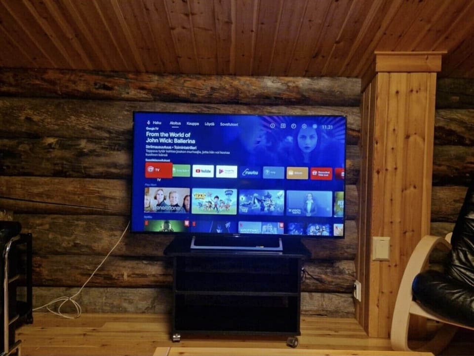 Smart TV with streaming apps mounted on the log wall in the living area.