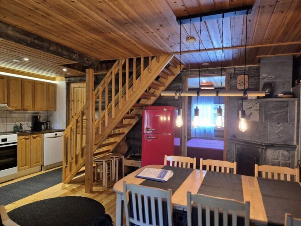 Open-plan kitchen and dining area with a table for six, beside the wooden staircase to the upper floor.