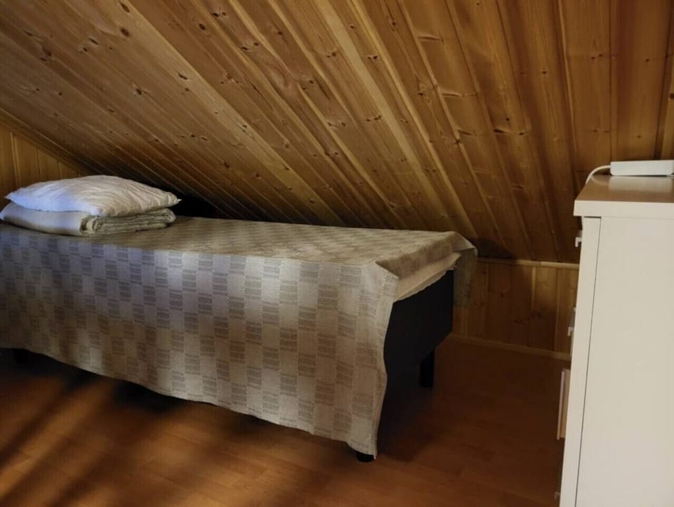 Cozy loft bed beneath the sloping wooden ceiling, with a chest of drawers for storage.