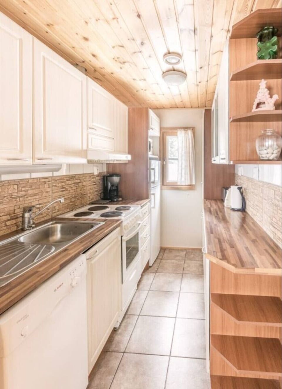 Well-equipped kitchen with an electric stove, oven, coffee maker, kettle and generous counter space.