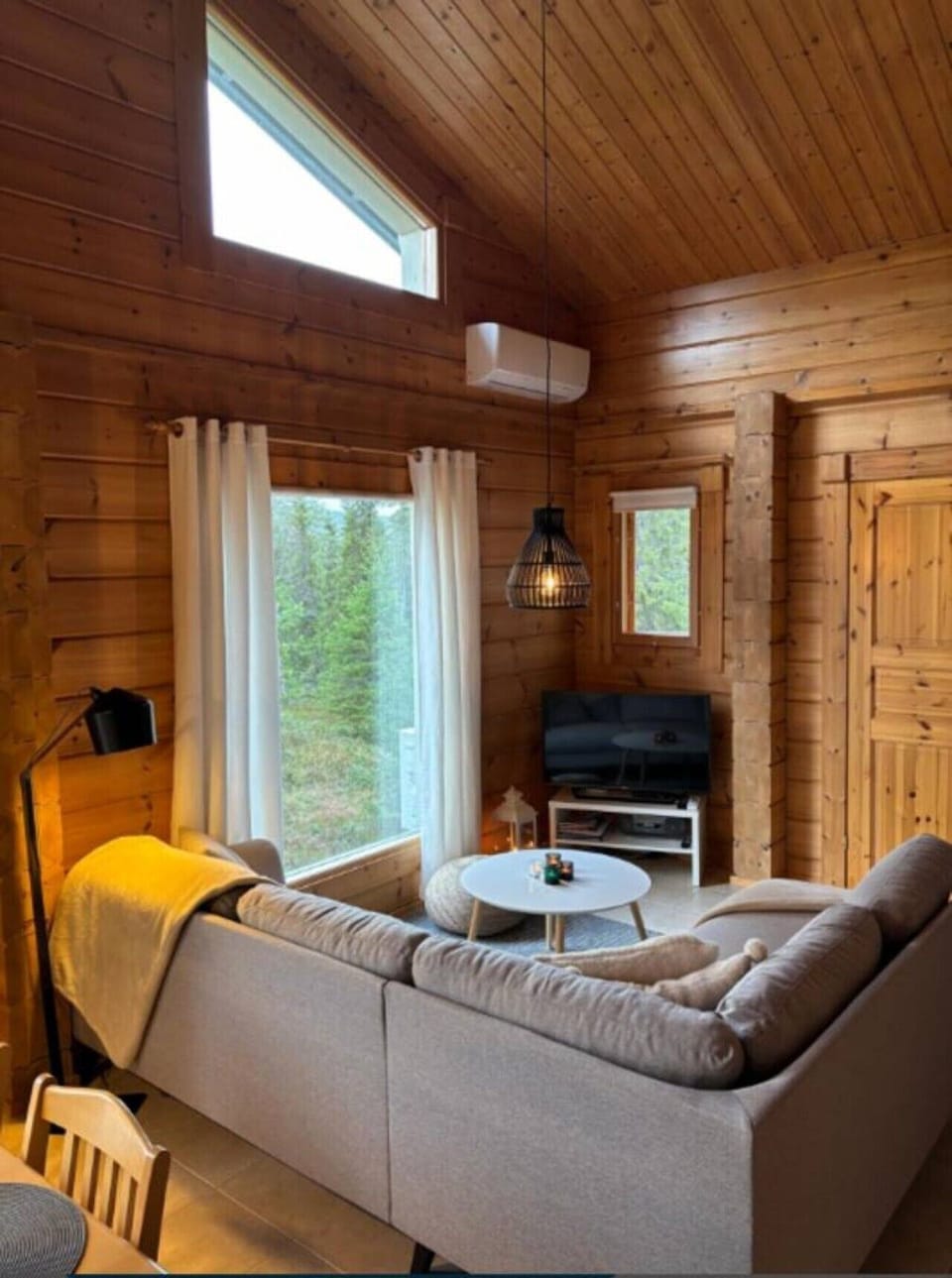 Living room seating beside a large window with a view of the surrounding forest.