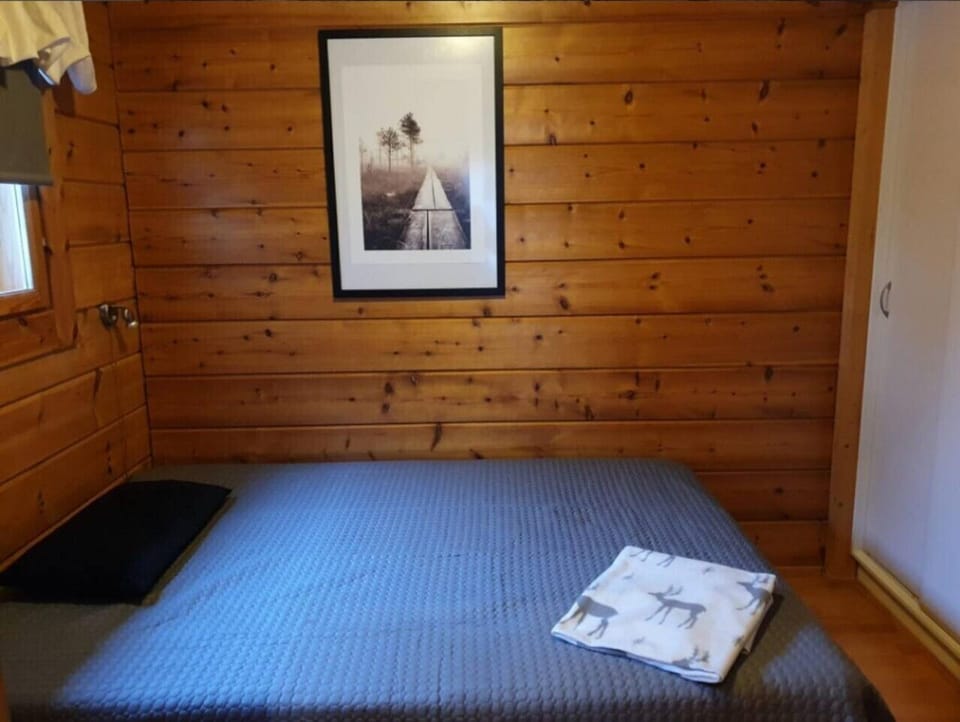 Bedroom with a double bed set against warm log walls.