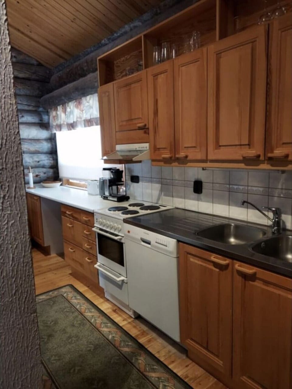 Kitchen worktop with an electric stove and oven, a coffee maker and a sink.