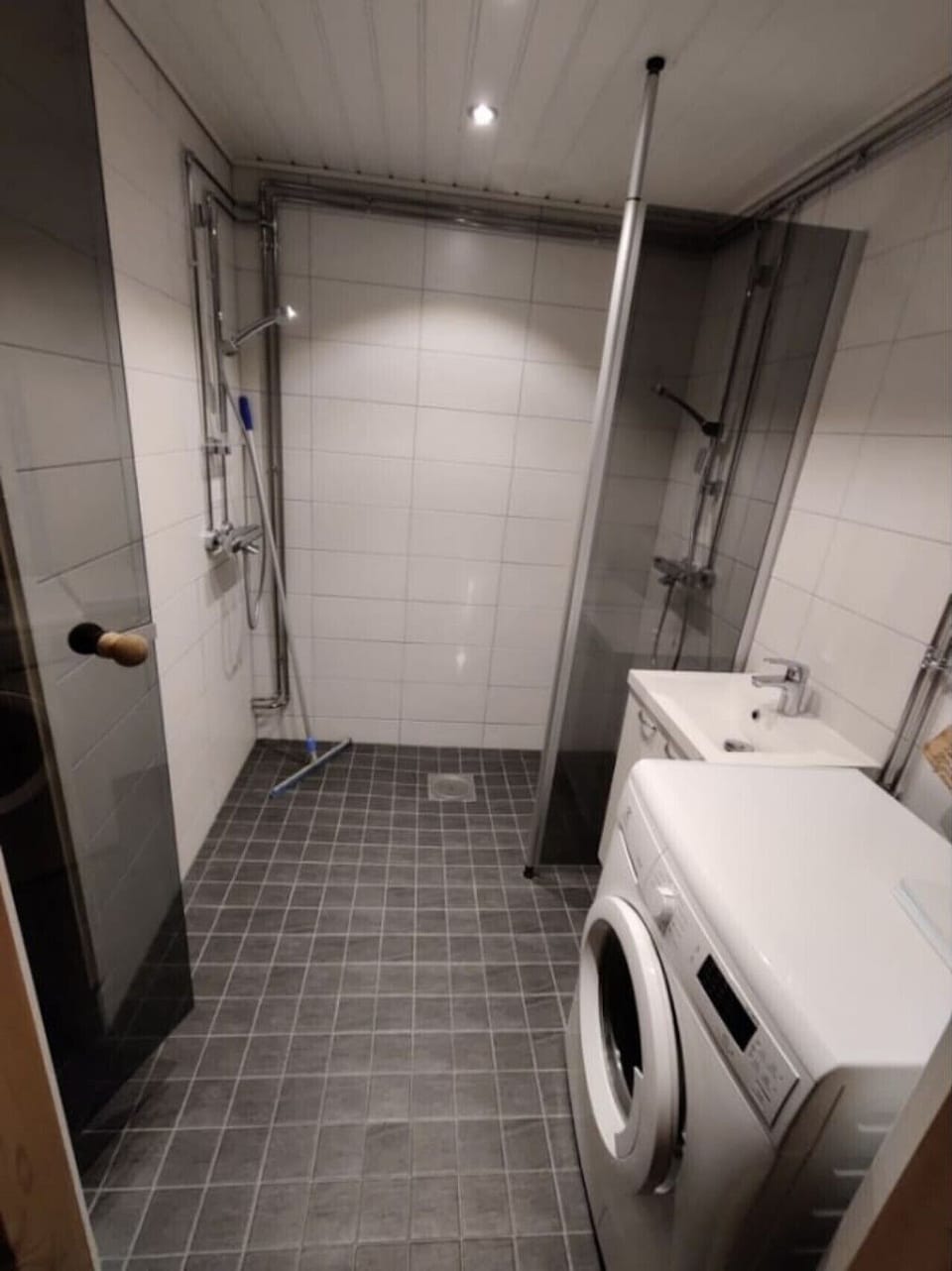 Shower room with a walk-in shower, a washbasin and a washing machine.