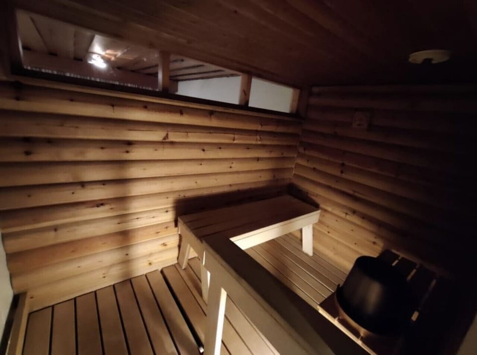 Traditional wooden sauna with tiered benches and an electric heater.