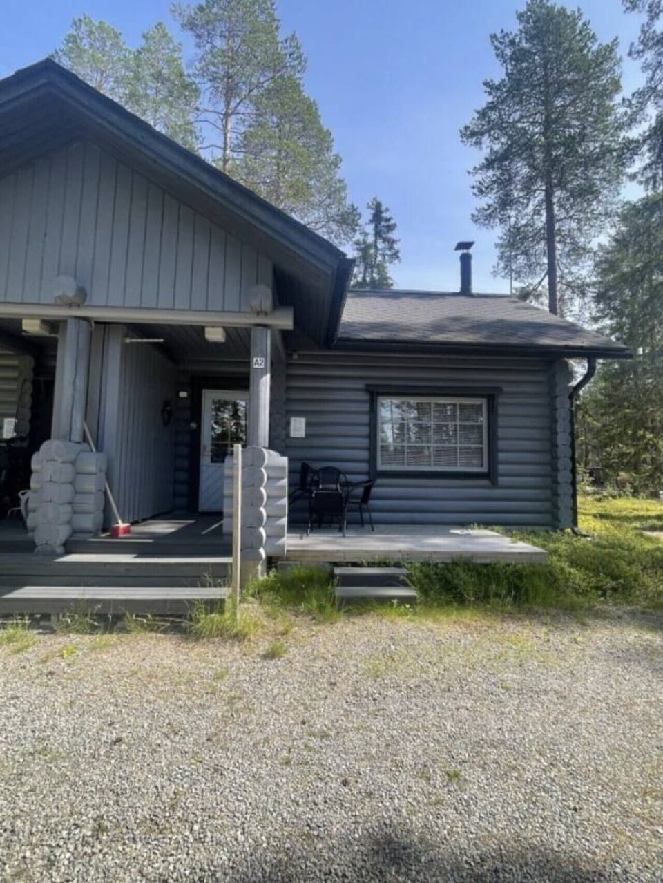 Exterior view of the cabin with an outdoor terrace and surrounding forest.