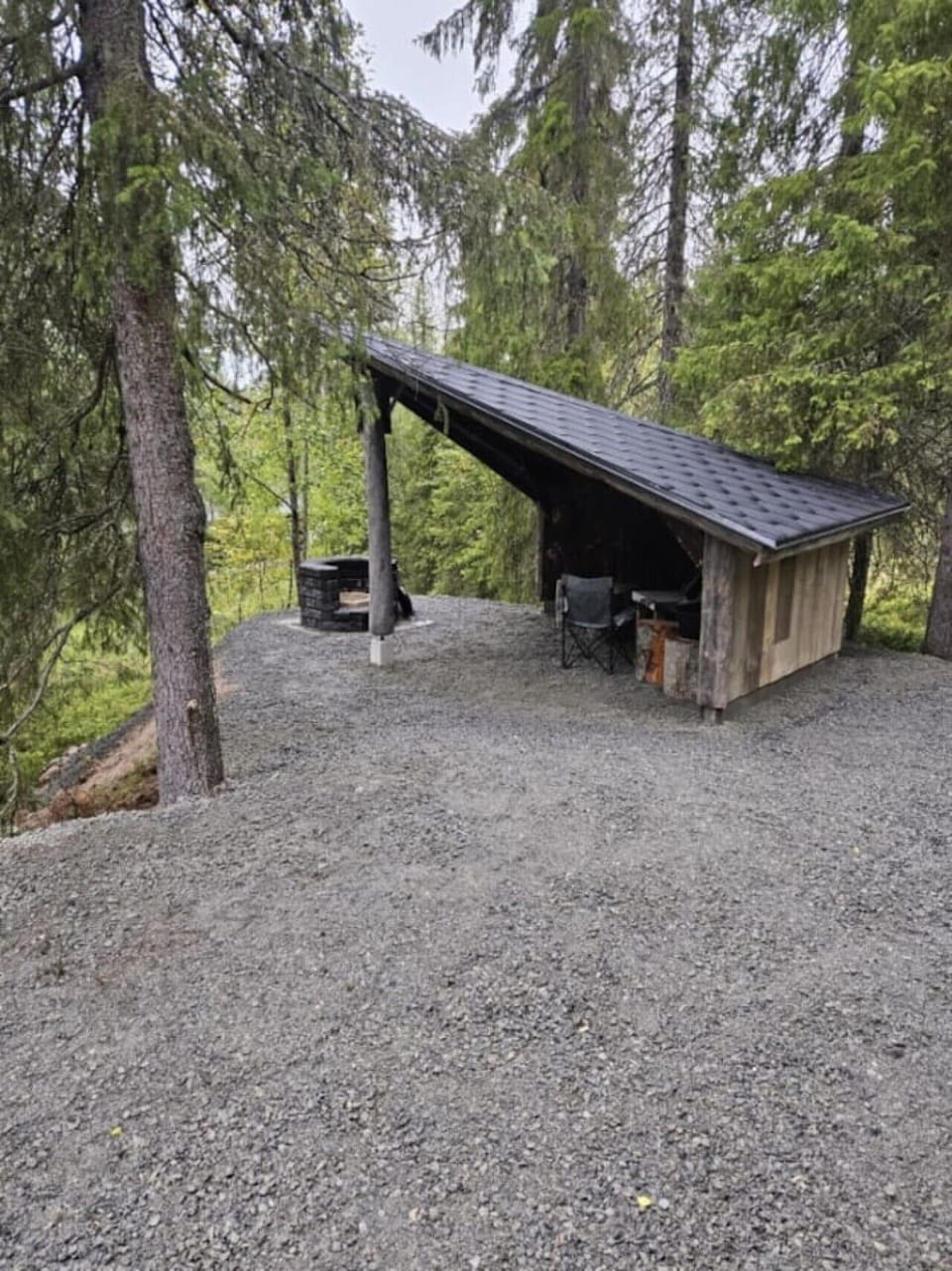 Covered outdoor shelter on the gravel yard beside the cabin.