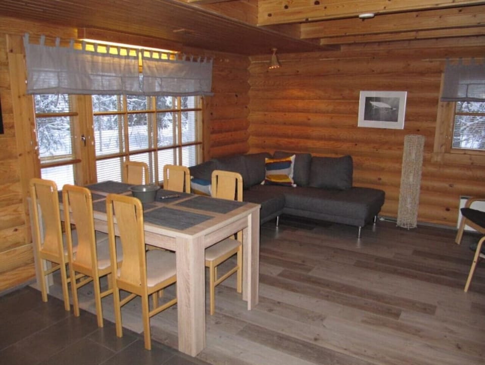 Bright living and dining area with a dining table and sofa beside large windows.
