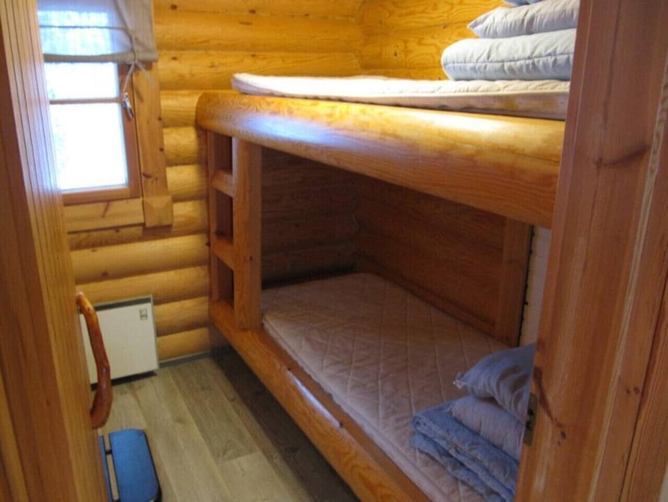 Bedroom with a bunk bed set against the log wall.