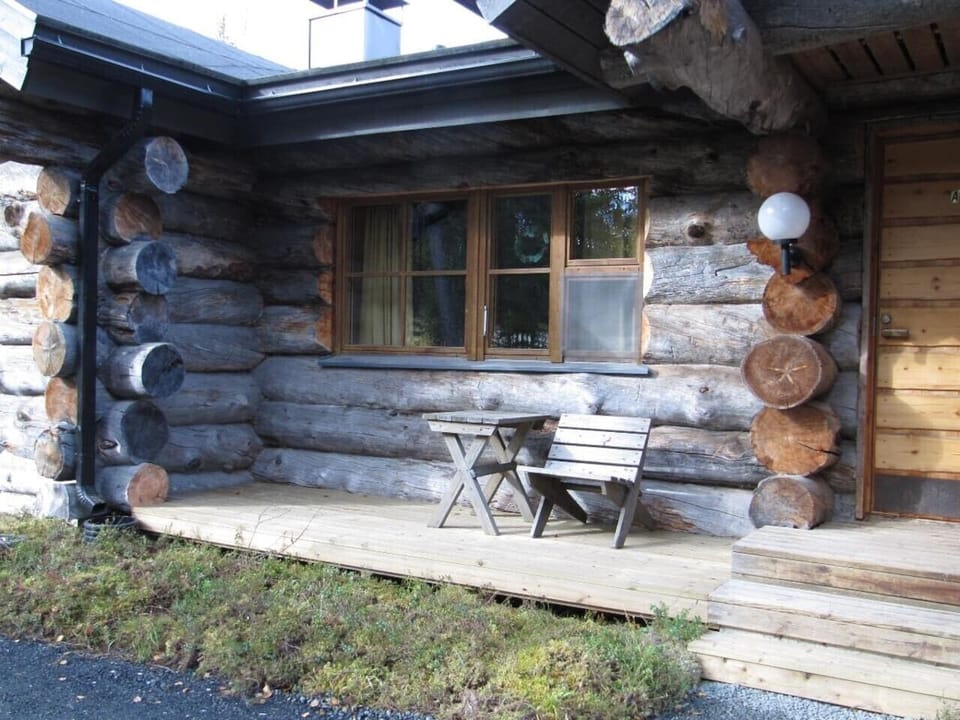 Outdoor table and chairs on the terrace beside the log wall.
