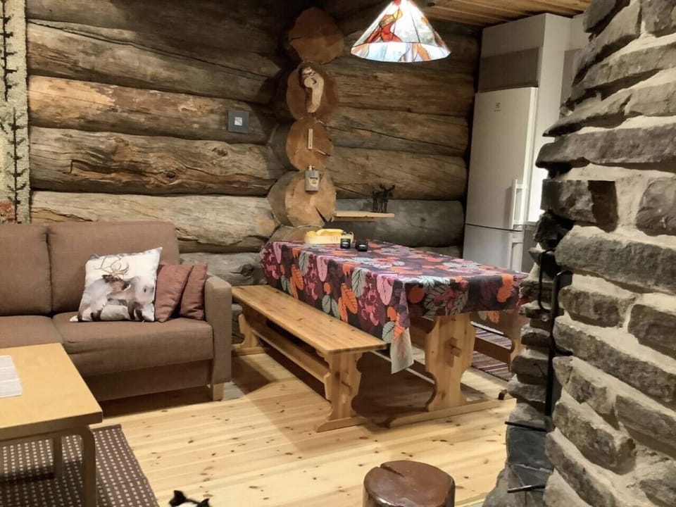Open-plan living and dining area with a sofa and log walls.