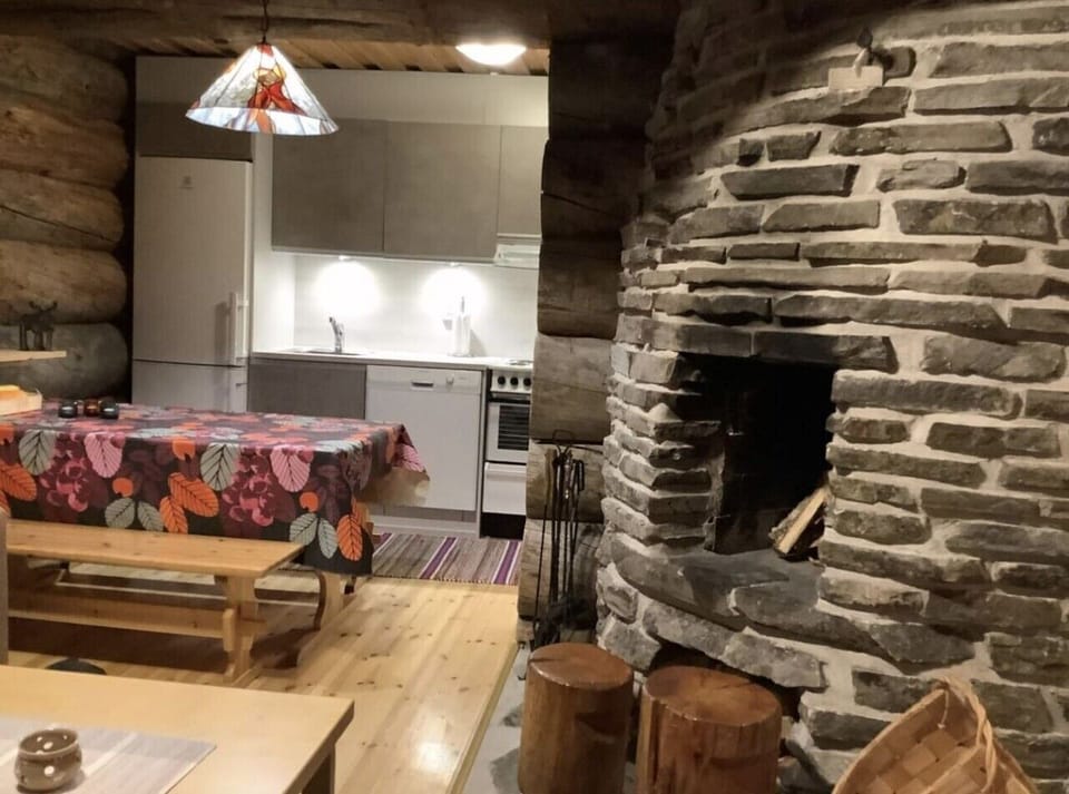 Dining table and kitchen area beside the large stone fireplace.