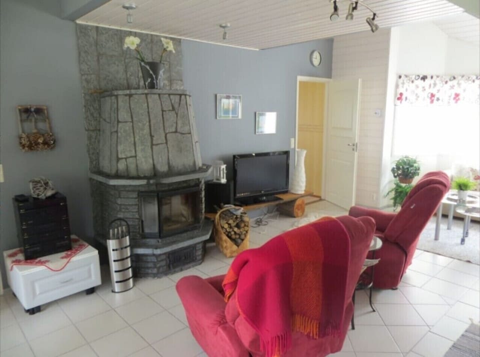 Living room with a stone fireplace, flat-screen TV and reclining armchairs.