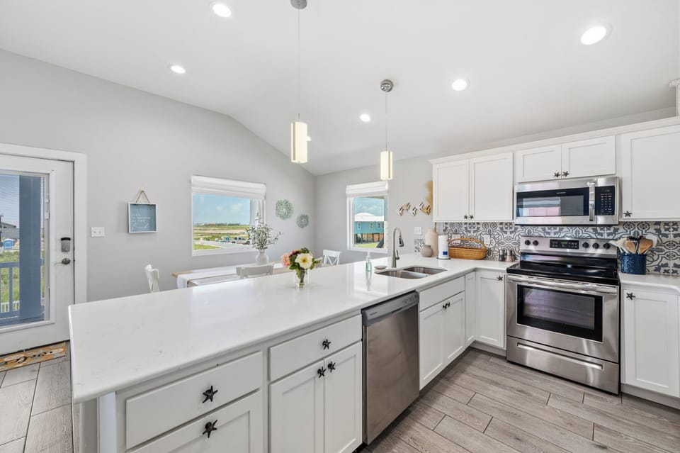 Step into this bright, airy kitchen where waterside living meets effortless style. With crisp white cabinetry, sleek stainless appliances, and a charming backsplash, you'll have everything you need to craft vacation memories together.