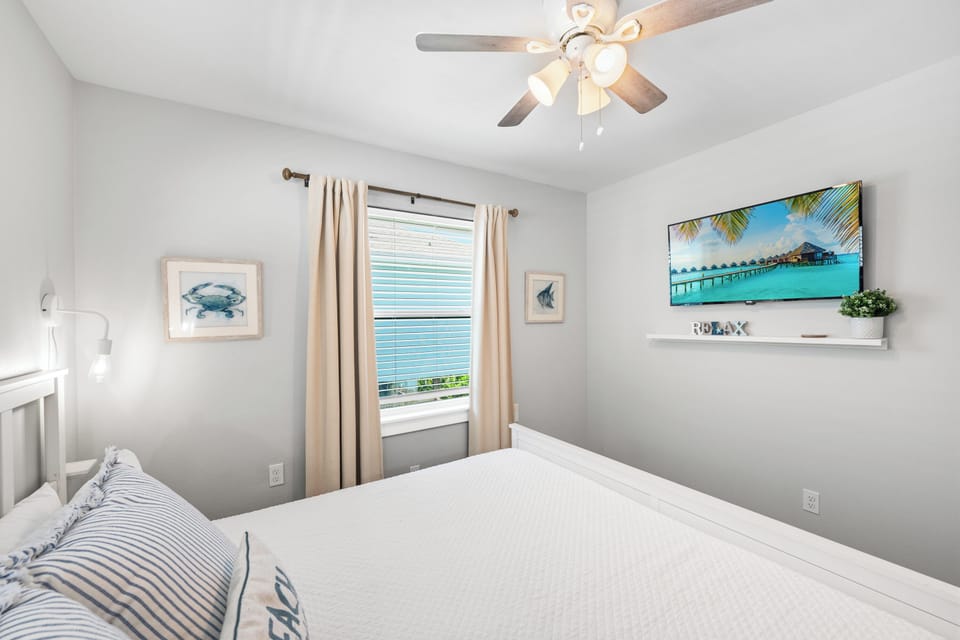 Rest easy in your serene bedroom with fresh linens, a gentle ceiling fan, and coastal touches that bring calm and comfort to your retreat.