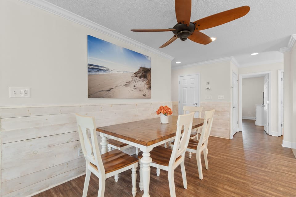 Gather around your charming dining table beneath coastal artwork that sets a relaxing beach house vibe for memorable meals together.