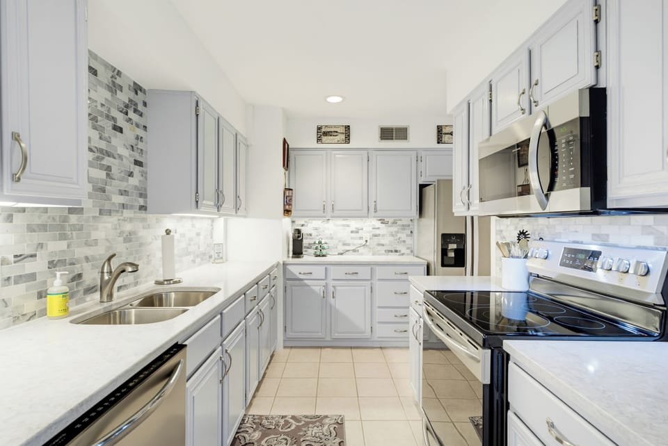 The fully equipped kitchen features quartz countertops, stainless steel appliances, and a tile backsplash.
