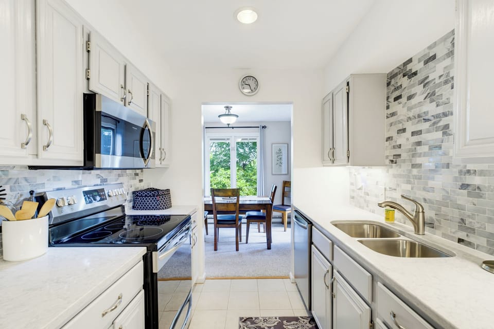 A bright, fully equipped kitchen opens directly to the dining area, with wooded views just beyond.
