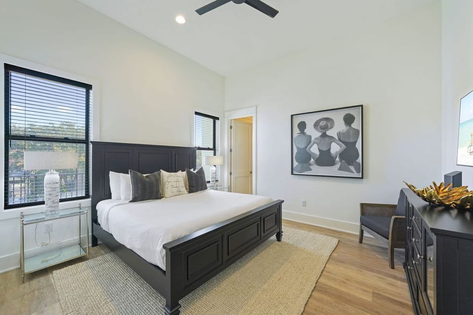 Sophisticated King Bedroom: Features a classic dark wood King bed frame, neutral decor, bright windows, and an en-suite vanity.