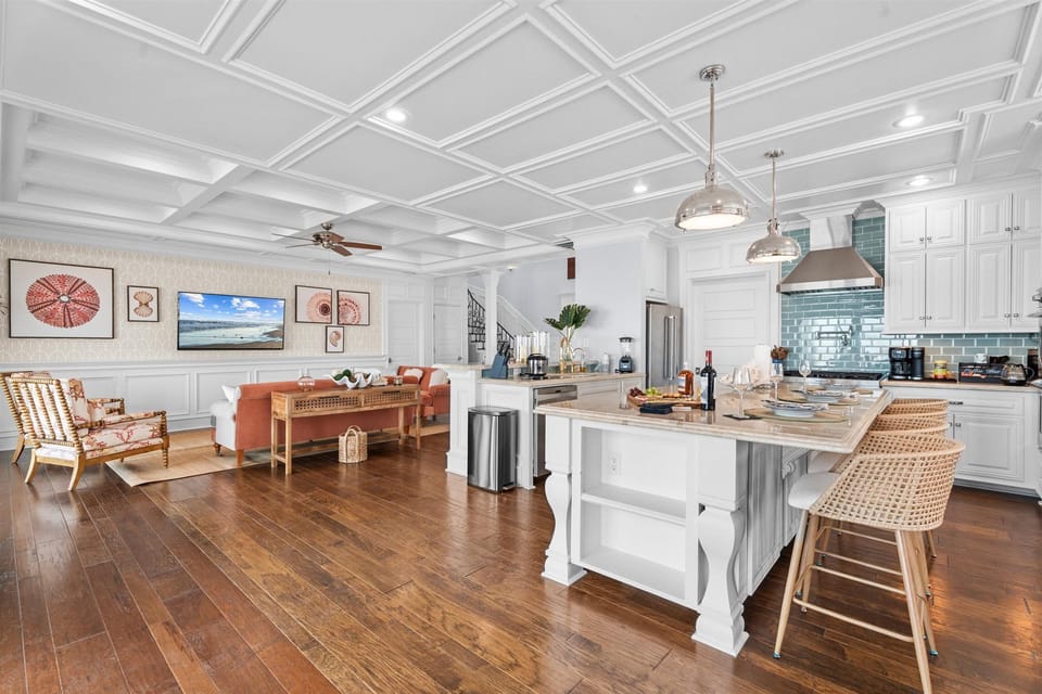 Bright open-concept kitchen and living area with a spacious island, bar seating, hardwood floors, and plenty of room for guests to gather.