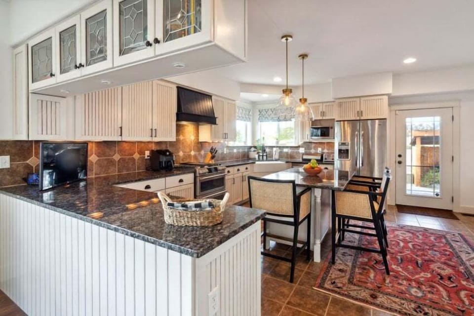 Open-style country kitchen featuring granite countertops, custom cabinetry, stainless steel appliance, spacious island and a breakfast bar