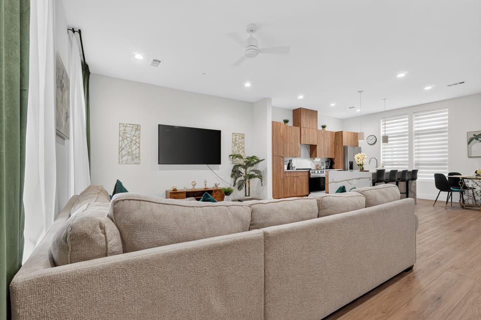 Bright open living space with large sectional, TV, and modern kitchen