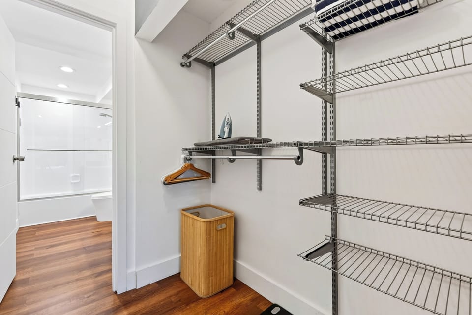 Open storage area with extensive wire shelving, hanging space, and full-length mirror.