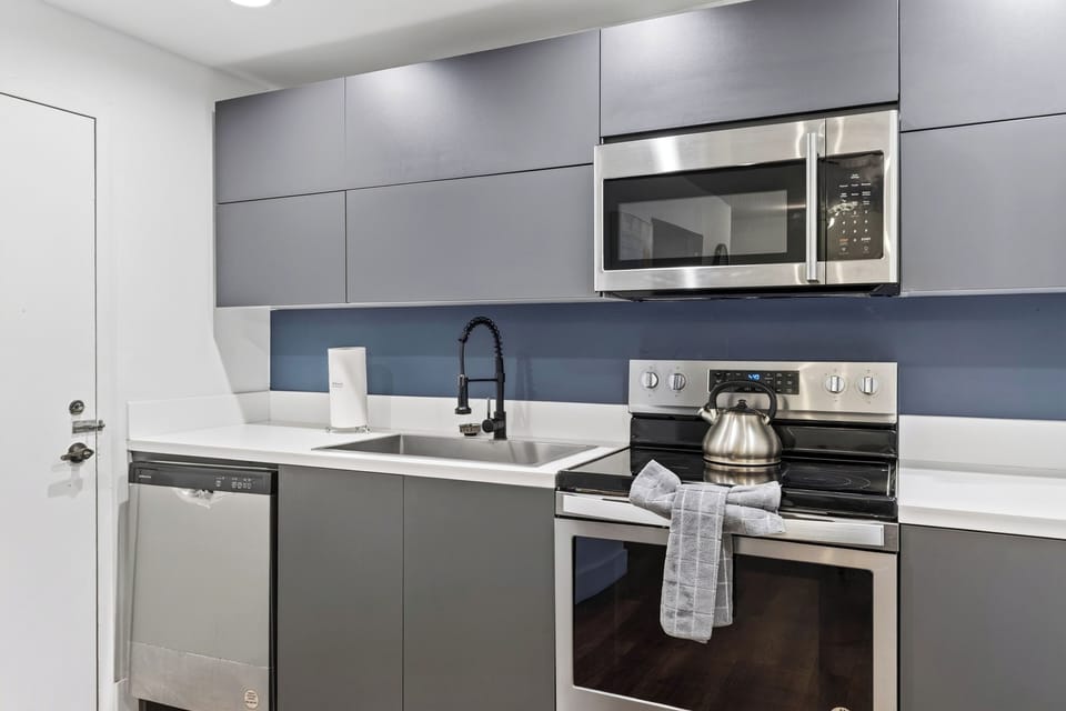 Contemporary kitchen workspace with stainless steel appliances and matte black fixtures.