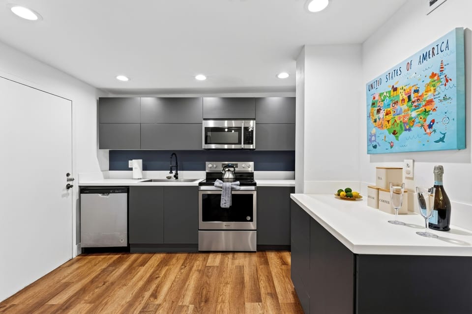 Sleek kitchen featuring stainless steel appliances, dark cabinetry, and bright countertops.