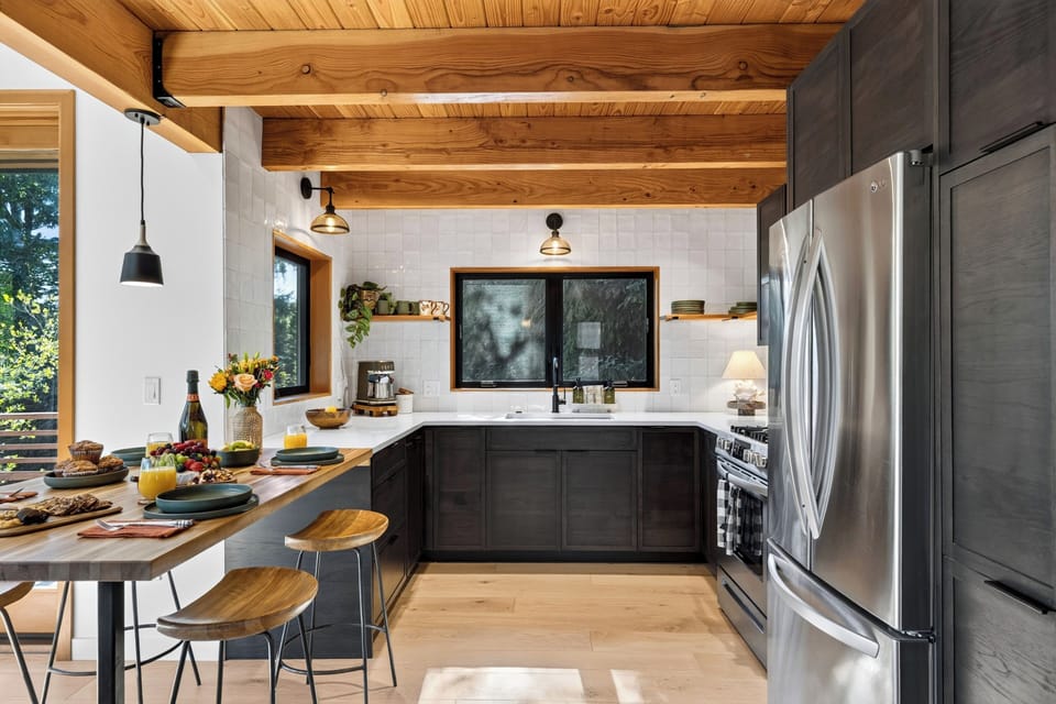 Warm kitchen entry with breakfast bar seating, wood-beamed ceilings, and cozy coastal cabin character.