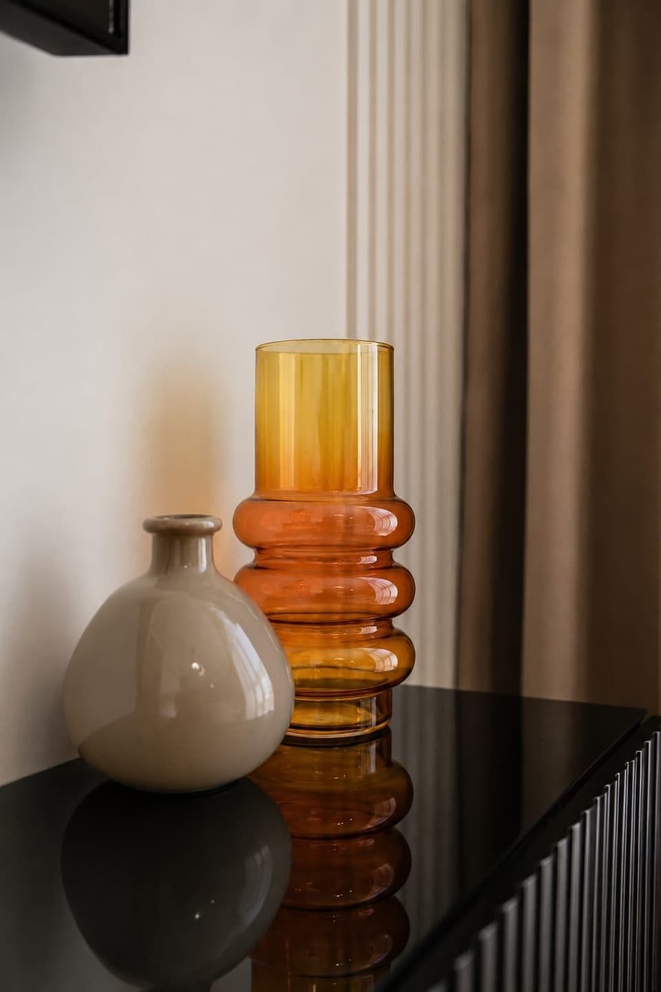 Decorative vases arranged beside a curtain in warm tones.