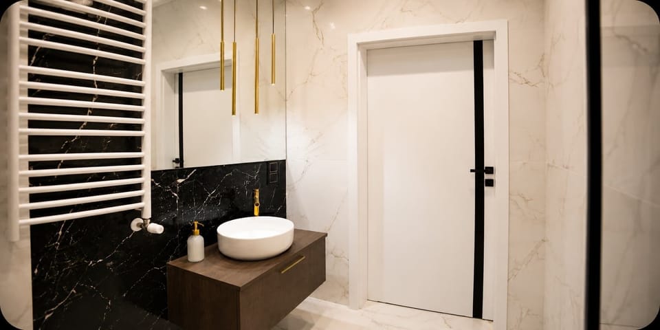 A bathroom vanity with a white sink, mirror, and heated towel rail.