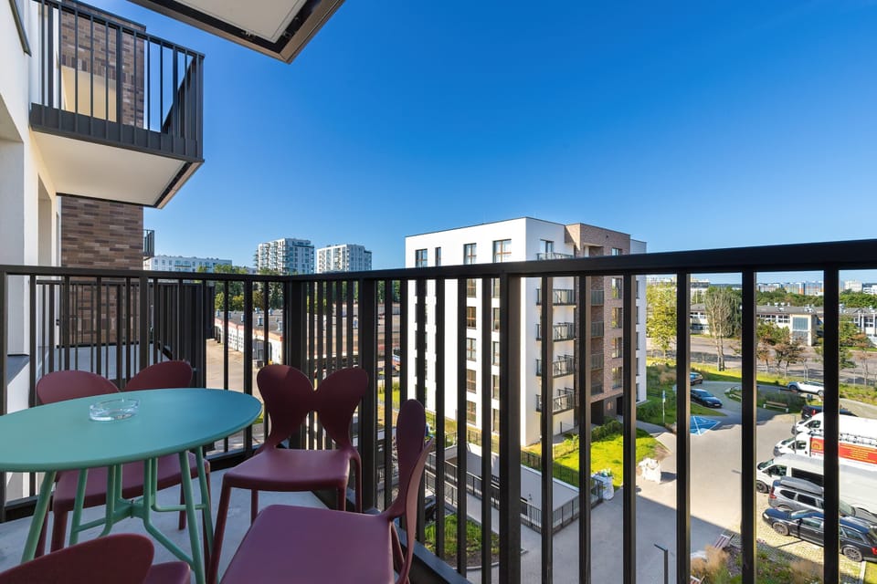 A balcony with outdoor seating, a table, and views of the surrounding buildings.