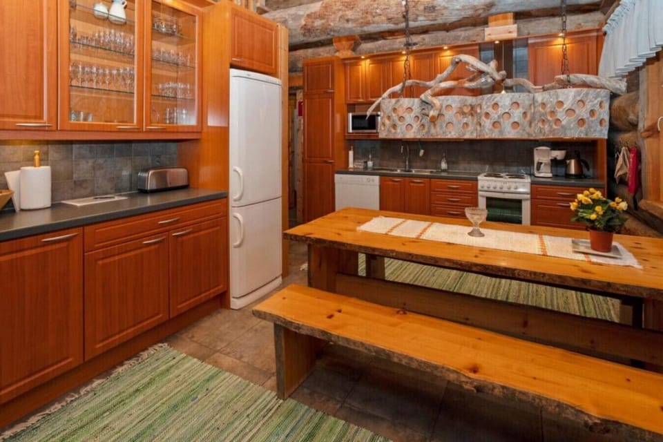Wooden kitchen with a fridge-freezer, oven and a long dining table with benches.