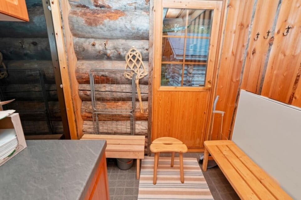 Log-walled changing area with a wooden bench and stool.