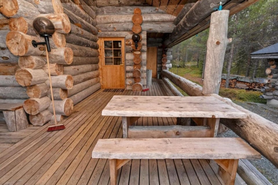 Covered wooden terrace with a rustic log table and benches for outdoor meals.