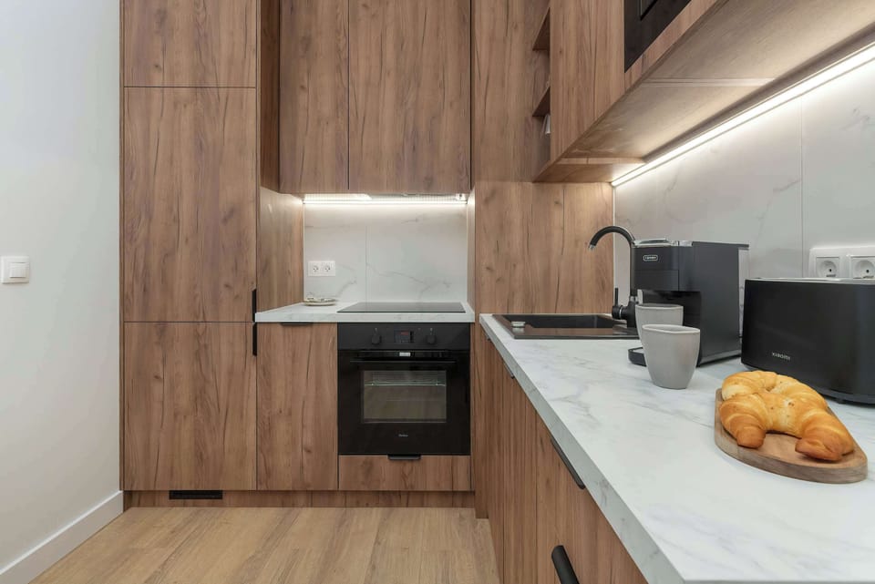 A modern kitchen countertop with a coffee machine, sink, and wooden cabinets.