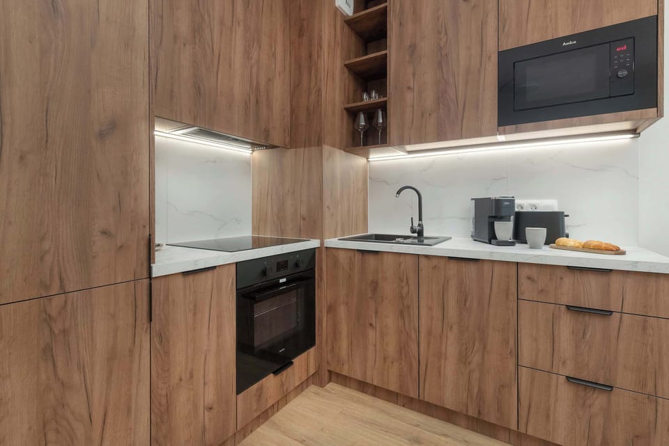 A modern wooden kitchenette with built-in appliances and a countertop.